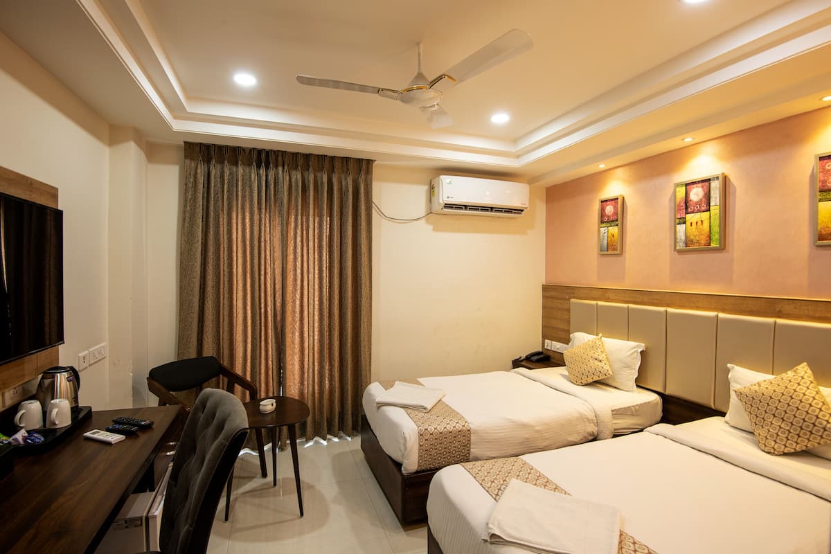 A hotel room with two beds, a desk with a chair, a television, and an air conditioning unit.