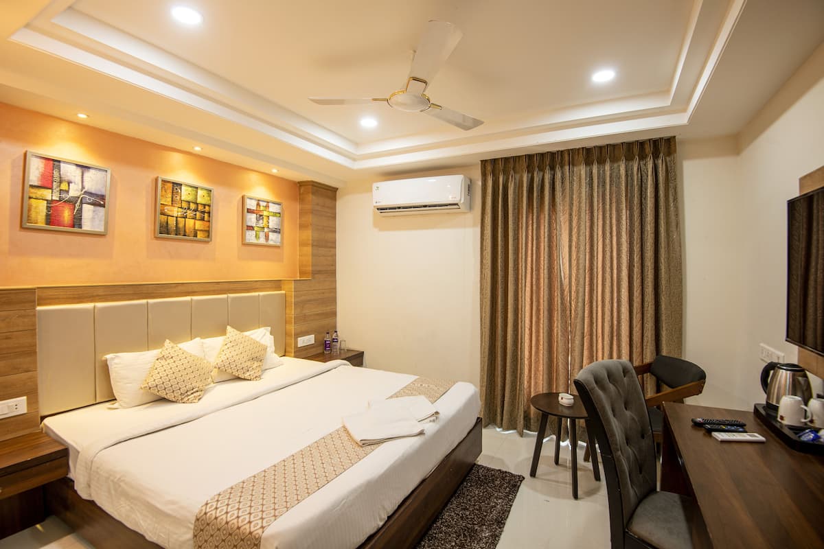 A hotel room with a large bed, a desk with a chair, a coffee maker, and a ceiling fan.