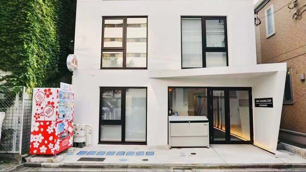A modern building with a white facade, multiple windows, and a ground-level entrance with a sign. - TIME SHARING STAY ikebukuro (Tokyo)
