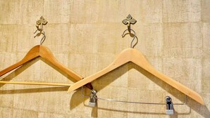 Two wooden hangers with metal clips against a textured wall. - TIME SHARING STAY ikebukuro (Tokyo)