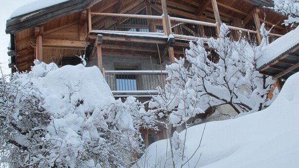 A wooden chalet with a balcony, surrounded by snow-covered trees. - Farmhouse in a mountain village hamlet (La Roche-de-Rame)