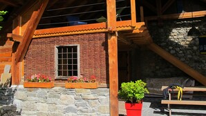 A rustic building with a stone facade, wooden beams, and a window with a grid pattern. - Farmhouse in a mountain village hamlet (La Roche-de-Rame)