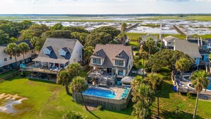 A large house with a swimming pool, surrounded by lush greenery and a view of a marshy landscape. - 1511 Forrest Ave - Sea Caught The Katy - Private Pool- Ocean Views-Best Surf at Washout (Folly Beach)