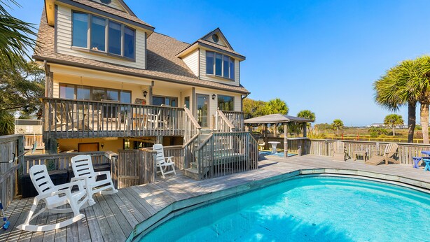 A two-story house with a swimming pool, deck chairs, and a wooden fence. - 1511 Forrest Ave - Sea Caught The Katy - Private Pool- Ocean Views-Best Surf at Washout (Folly Beach)