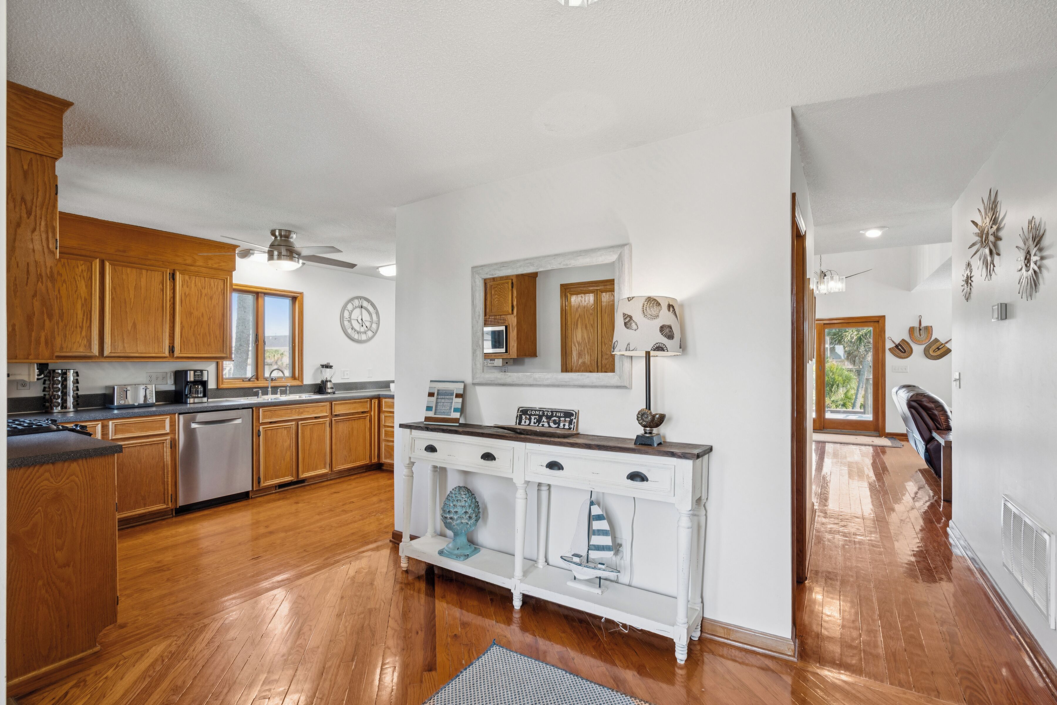A modern kitchen with wooden cabinets, stainless steel appliances, and a white console table.