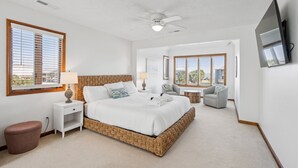 A bedroom with a large bed, a ceiling fan, a TV mounted on the wall, and a window with blinds. - 1511 Forrest Ave - Sea Caught The Katy - Private Pool- Ocean Views-Best Surf at Washout (Folly Beach)