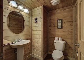 A wooden-paneled bathroom with a sink, mirror, and toilet. - Hillside Dreams #265 (Sevierville)