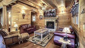 A log cabin interior with a fireplace, leather sofas, and a stone wall. - Hillside Dreams #265 (Sevierville)