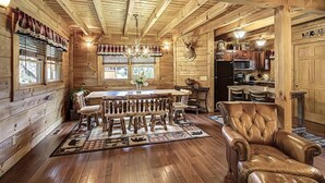 A rustic cabin interior with a wooden dining area, leather chair, and a kitchen with wooden cabinets. - Hillside Dreams #265 (Sevierville)