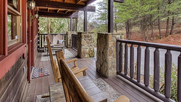 A wooden deck with stone pillars, wooden railings, and a bench. - Hillside Dreams #265 (Sevierville)