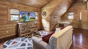 A log cabin interior with a television, a fireplace, a sofa, and a patterned rug. - Hillside Dreams #265 (Sevierville)