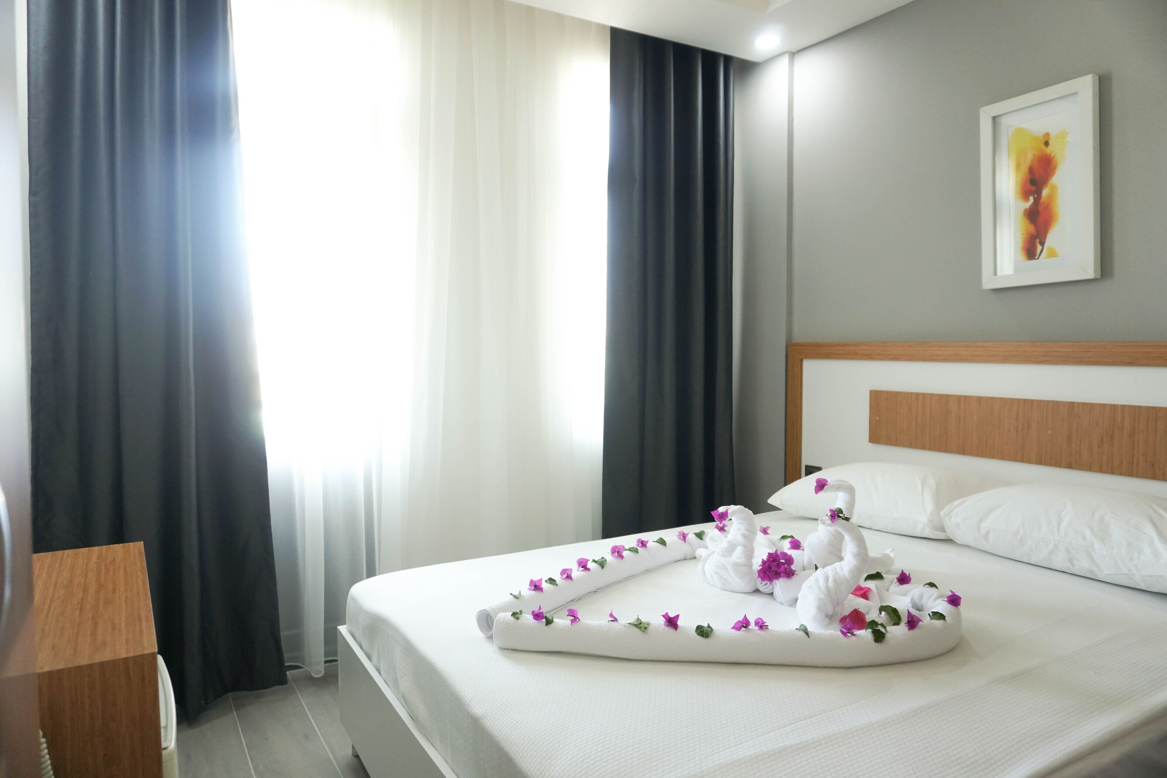 Een hotelkamer met een net opgemaakt bed, een houten hoofdbord en een schilderij aan de muur.