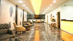 A modern lobby with a reception desk, seating area, and a glass wall. - Akalia Resort Hotel (Manavgat)