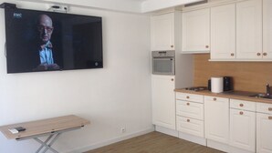 A modern kitchen with white cabinets, a built-in oven, and a wooden countertop.