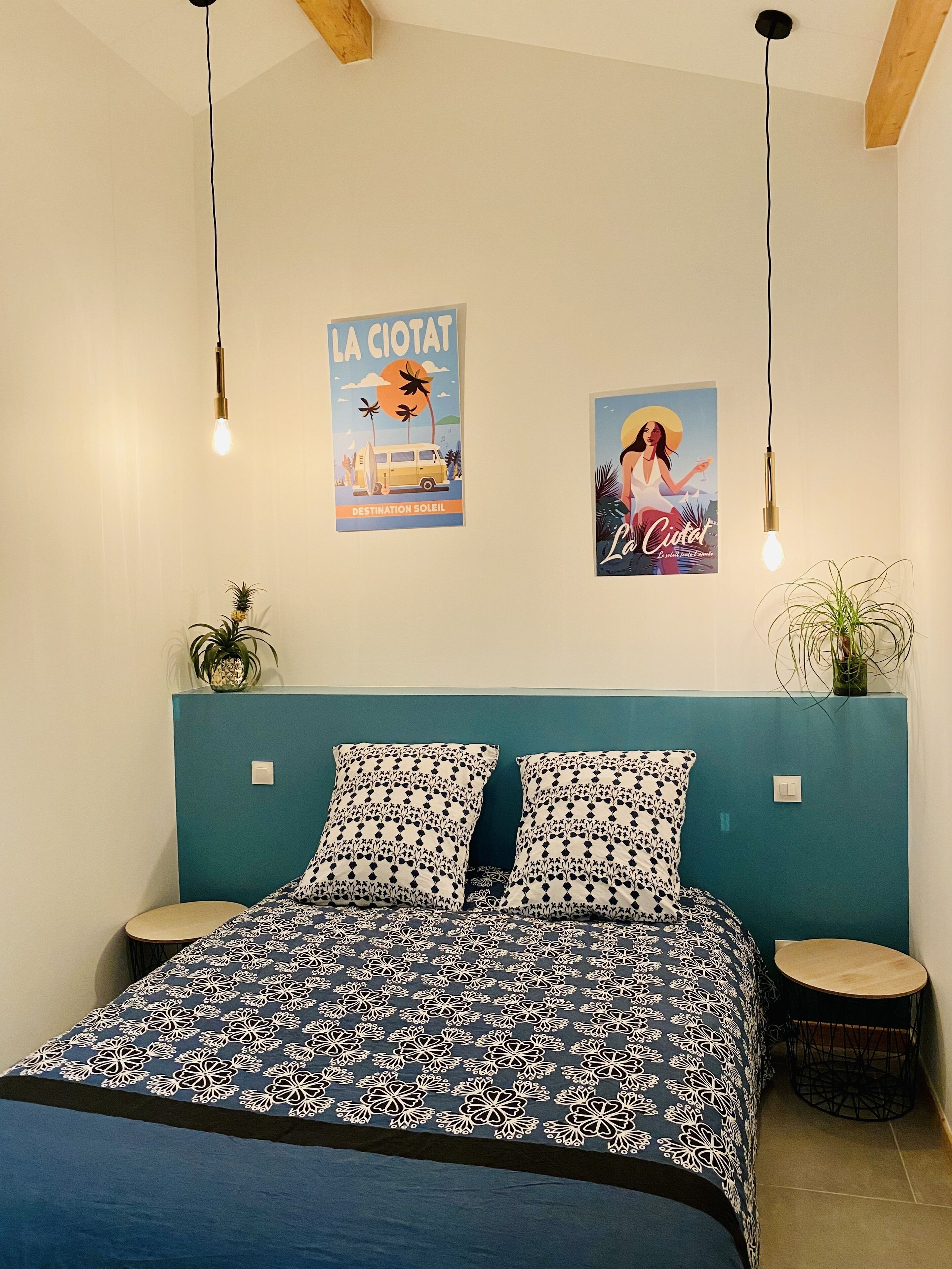 A bedroom with a bed, two wall-mounted light fixtures, a poster, and a small round table.
