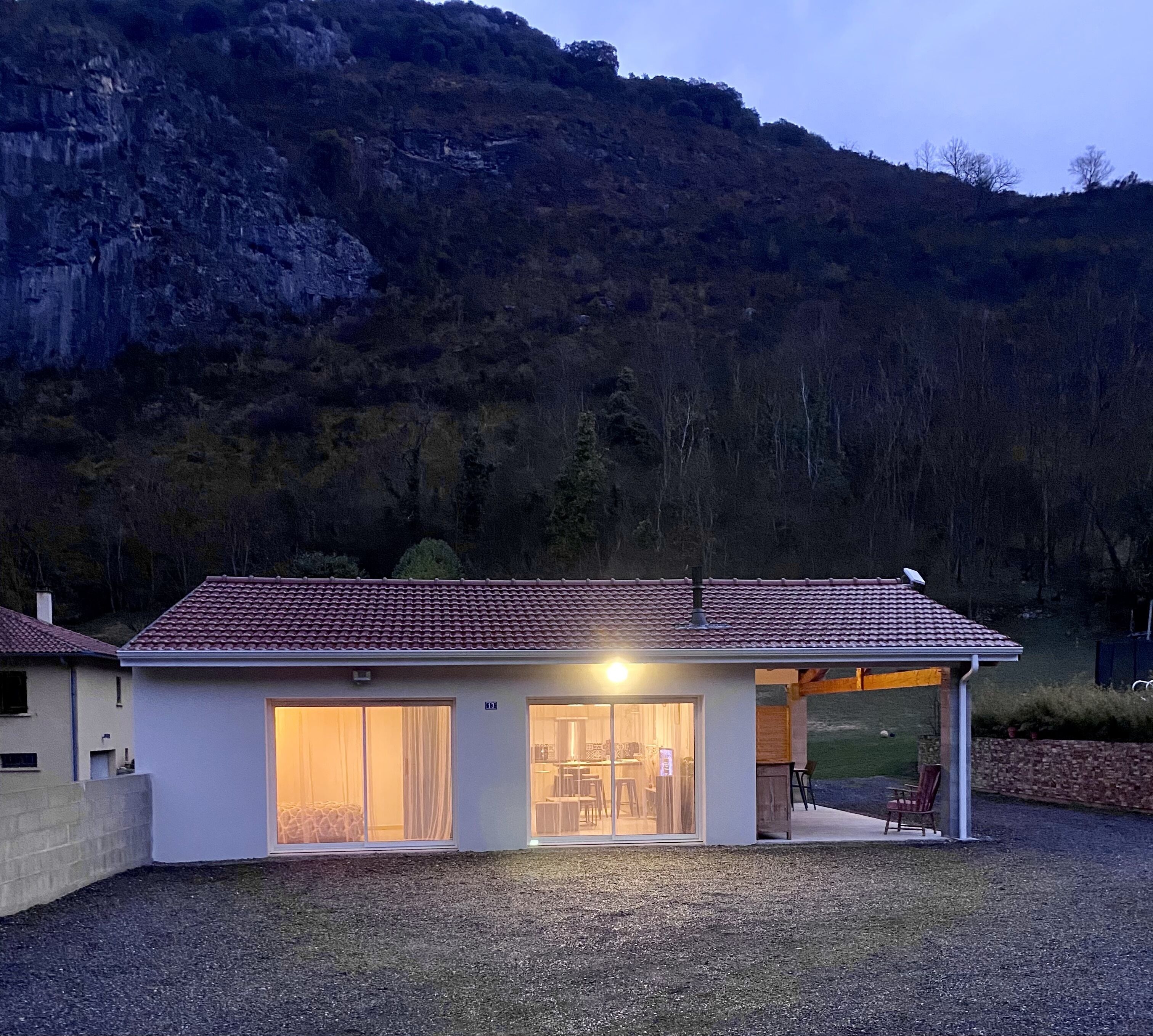 A modern house with a tiled roof, large windows, and a covered patio area.