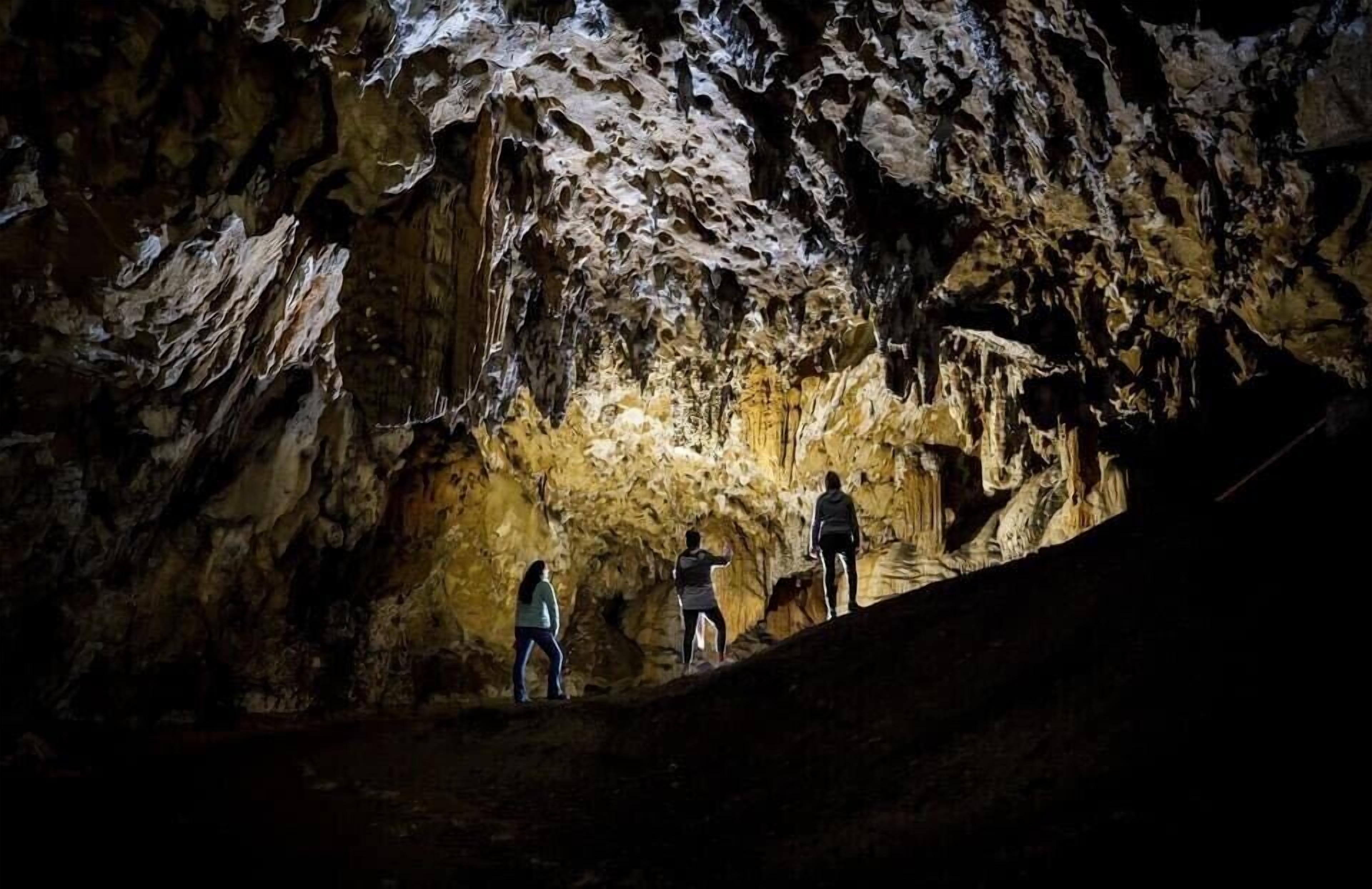 A cave interior with uneven rock formations and a group of people exploring.