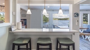 Una cocina moderna con una isla grande, luces colgantes y vistas al lago.