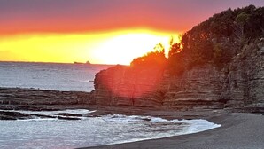 A coastal sunset with a rocky cliff and ocean waves.