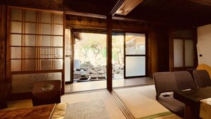A traditional Japanese room with tatami flooring, a low table, and a sliding door leading to a garden.