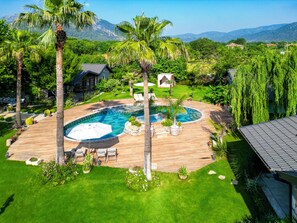 A backyard with a swimming pool, palm trees, and a well-maintained lawn. - Kaya Villas Exclusive (Fethiye)