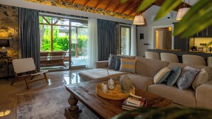 A spacious living room with a wooden ceiling, a large sofa, a coffee table, and a wicker chair. - Kaya Villas Exclusive (Fethiye)
