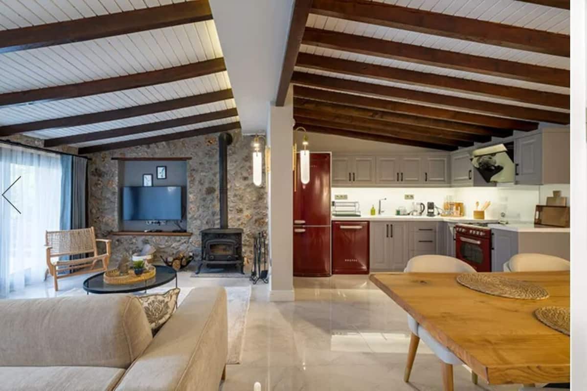 A modern kitchen with wooden beams, a dining area with a wooden table, and a bathroom with a blue tiled wall.