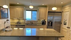 A modern kitchen with a central island, stainless steel appliances, and pendant lighting. - CP 614 Golf Course View Condo - Paradise Vacation Rental in Ocean Village (Fort Pierce)