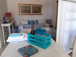 A neatly arranged bedroom with a bed, pillows, a bedside table with a lamp, and a painting on the wall.