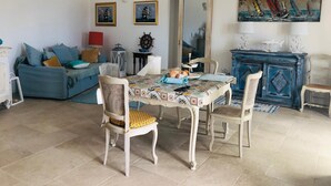 Un coin repas avec une table dressée pour deux personnes, un canapé bleu, un miroir et un tableau accroché au mur.