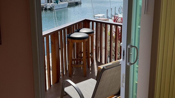 Ein Balkon mit Blick auf eine Marina, ein Boot und eine entfernte Insel.