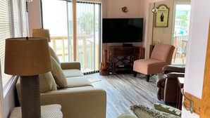Ein gemütliches Wohnzimmer mit einer Couch, einem Sessel und einem Fernseher.
