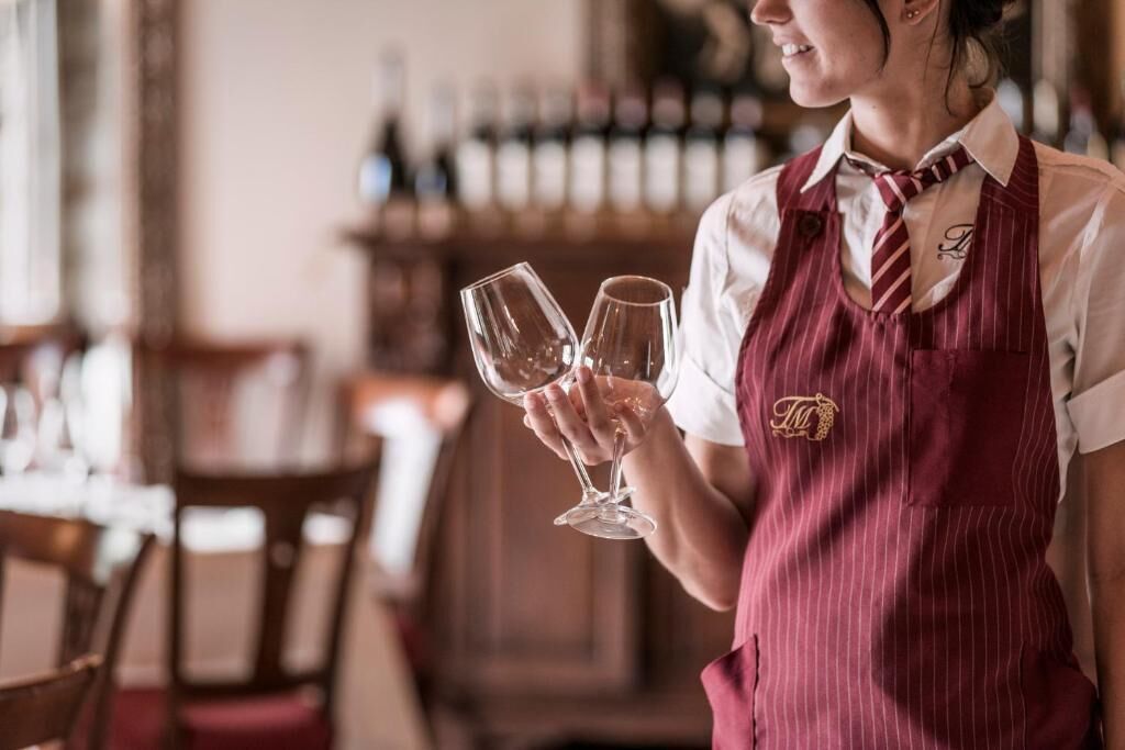 Une personne, assise dans un restaurant, tient deux verres à vin.