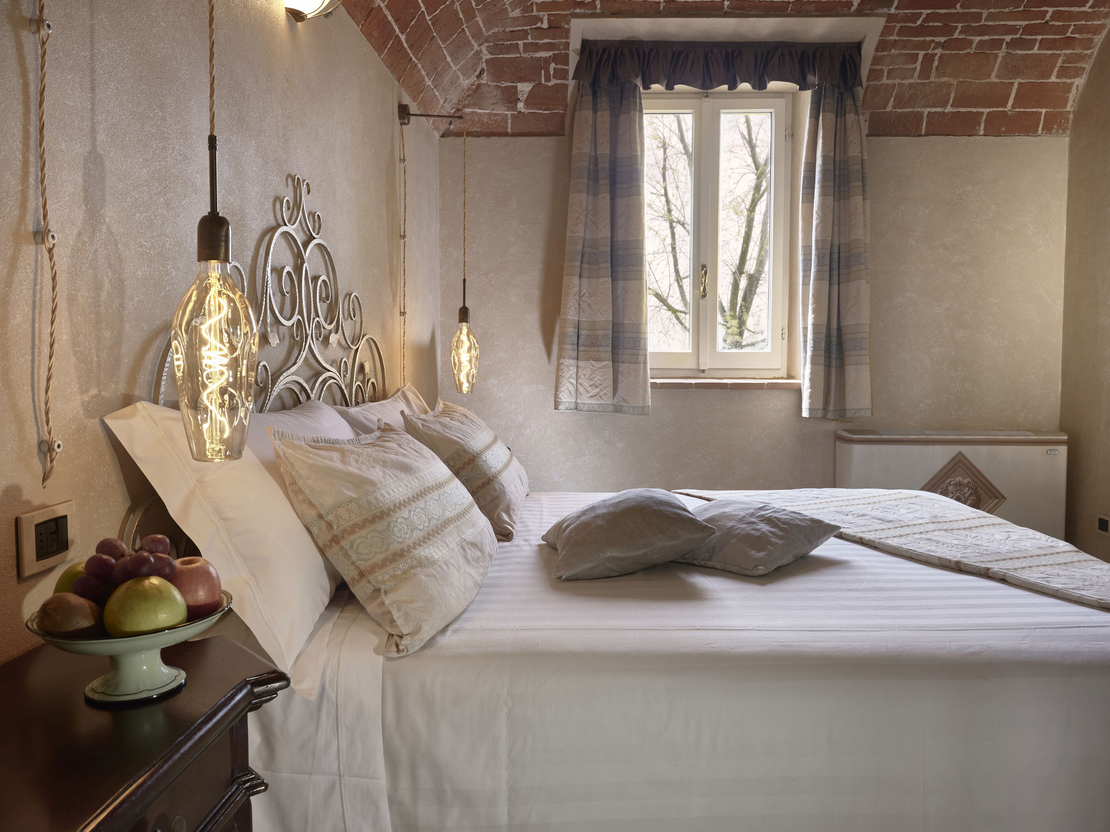 A bedroom with a bed, bedside table, and a window with curtains.