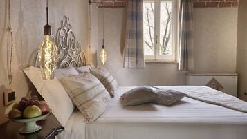 A bedroom with a bed, bedside table, and a window with curtains.