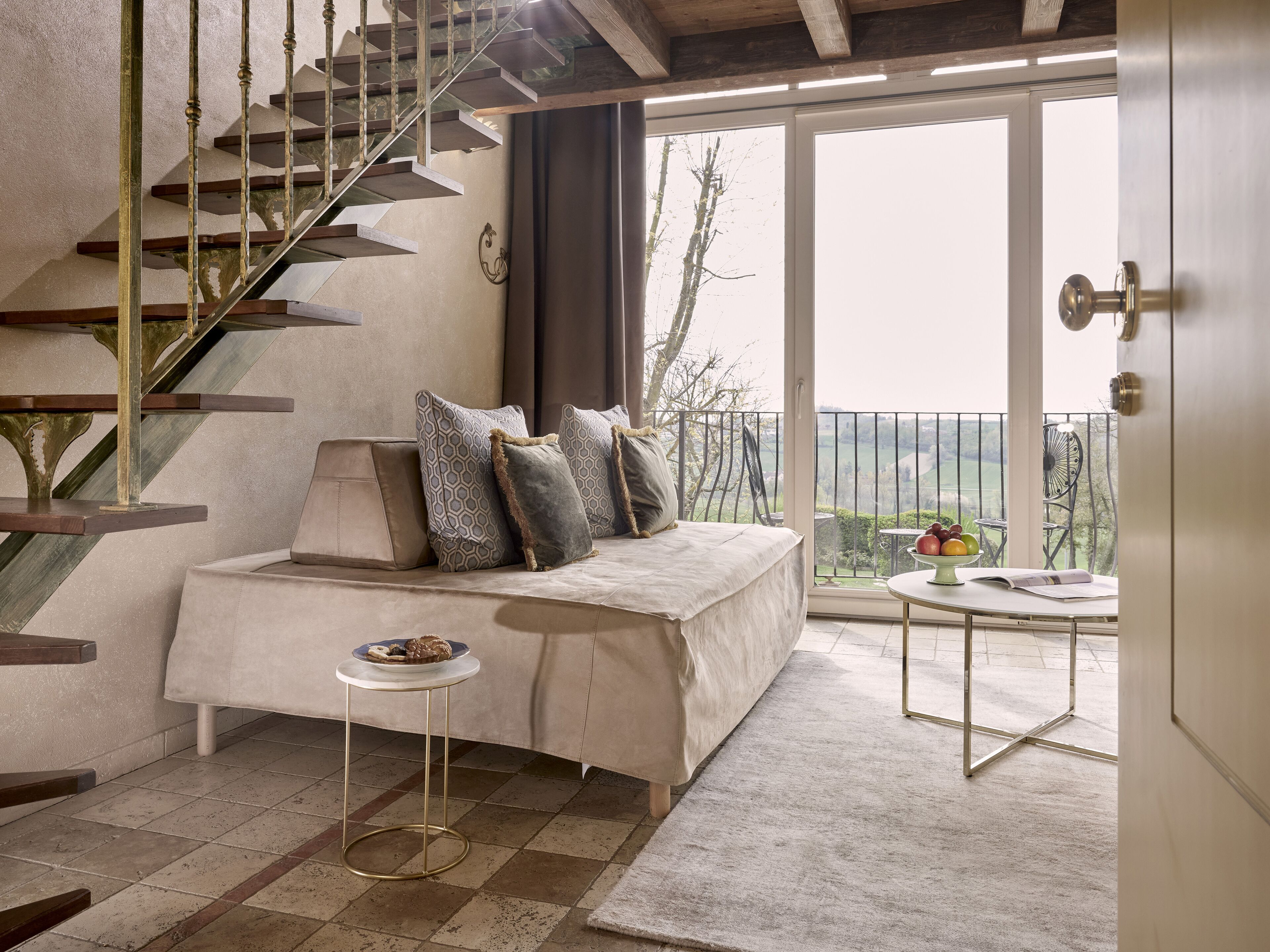 Un dormitorio con una cama, una mesita redonda pequeña, una escalera y un balcón con vistas.