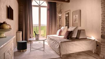 Un dormitorio acogedor con cama, mesita de noche y vistas a un paisaje verde a través de una ventana.