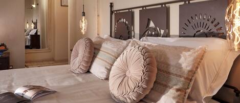 A neatly made bed with multiple pillows and a magazine on it.