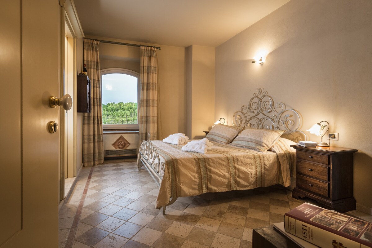 A bedroom with a bed, a nightstand, a dresser, and a window with curtains.