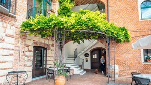 A courtyard with brick walls, a pergola covered in greenery, outdoor seating, and a staircase leading to an upper level. - Tenuta Montemagno (Montemagno)