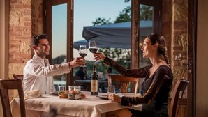 A couple toasting at a table with wine glasses, a bottle of wine, and a candle on a table with a view outside. - Tenuta Montemagno (Montemagno)