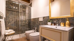 A modern bathroom with a glass shower enclosure, a toilet, and a vanity with a mirror. - Apartment (Venezia)