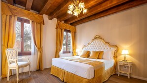 A bedroom with a large bed, a chair, a nightstand, and a chandelier. - Apartment (Venezia)