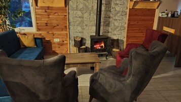 Un salón acogedor con chimenea de piedra, paredes de madera y asientos cómodos.