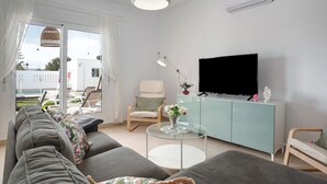 Ein modernes Wohnzimmer mit einer Couch, einem Glastisch, einem Fernseher und einem Sessel.