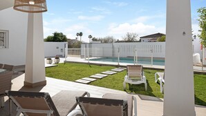 Eine Außenpatio mit Lounge-Möbeln, einem Pool und einem gepflegten Rasen.