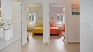 Ein Hotelzimmer mit zwei Betten, einem Spiegel, einer Vase mit Blumen und einem Gemälde an der Wand.