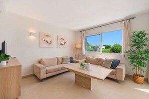 A modern living room with a sectional sofa, a coffee table, a desk, and a large window with curtains. - Holiday Home Rocas del Mar with Sea View, Pool, Garden & Wi-Fi (Mijas Costa)
