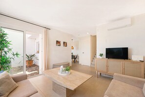A modern living room with a sofa, a coffee table, a television, and a dining area in the background. - Holiday Home Rocas del Mar with Sea View, Pool, Garden & Wi-Fi (Mijas Costa)