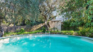 A swimming pool surrounded by trees and a stone wall. - House with Pool and Sea Views - Casa Can Divertit (Can Budella)